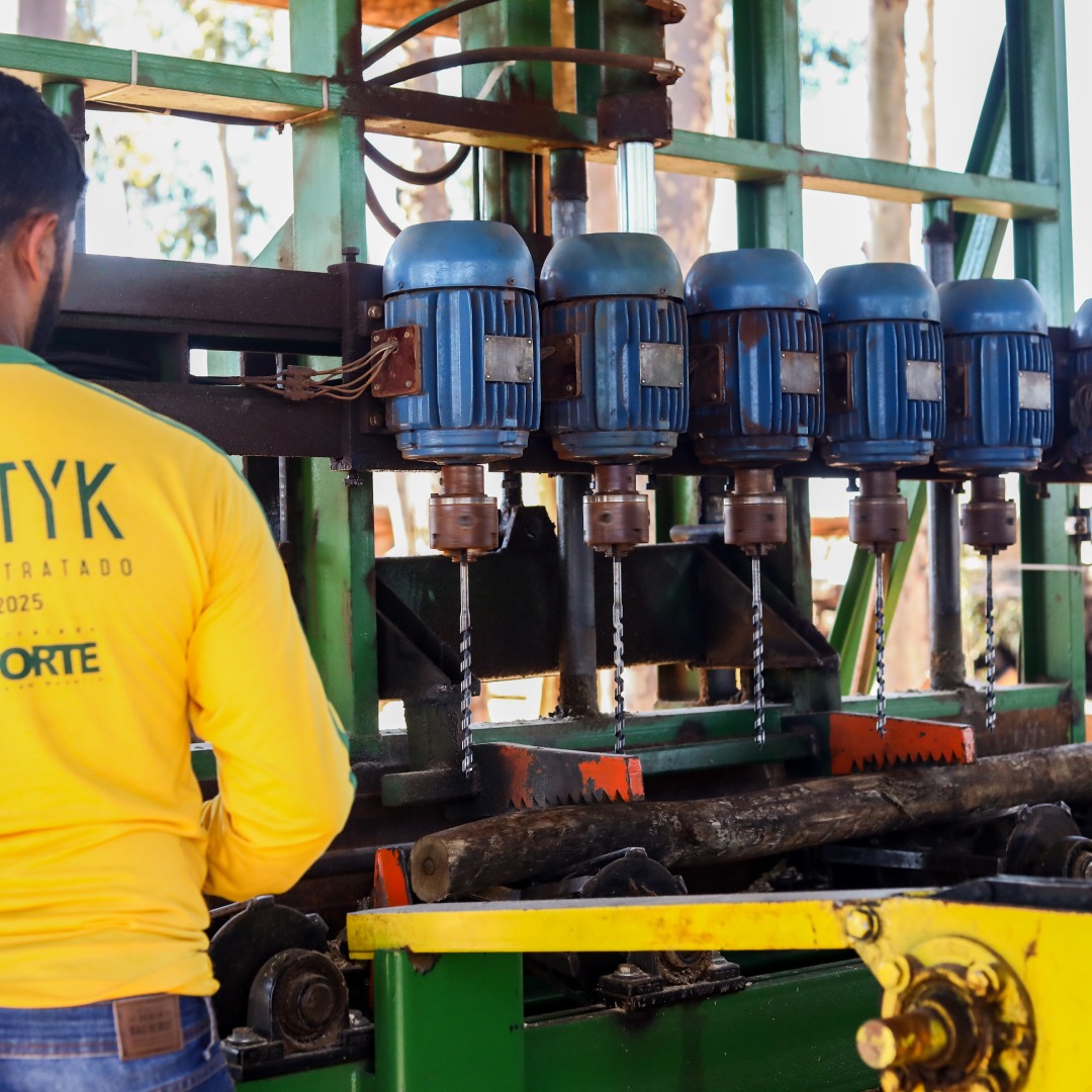 Colaborador Petyk de costas com camiseta amarela trabalhando com furadeiras de bancada